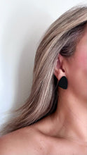 Load image into Gallery viewer, Model wearing matte black  organic shaped stud earrings handmade from polymer clay by Vertseas for size reference.
